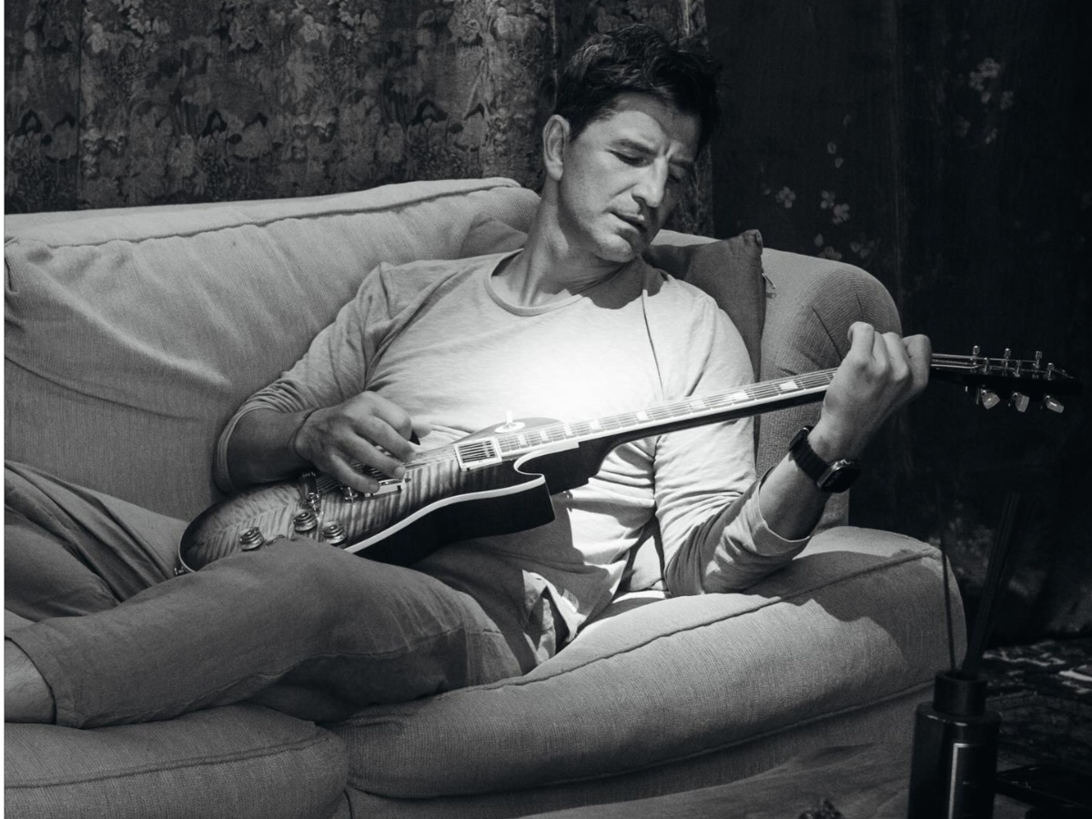 Σάκης Ρουβάς: Ερμηνεύει το νέο του τραγούδι παίζοντας κιθάρα στον καναπέ του σπιτιού του